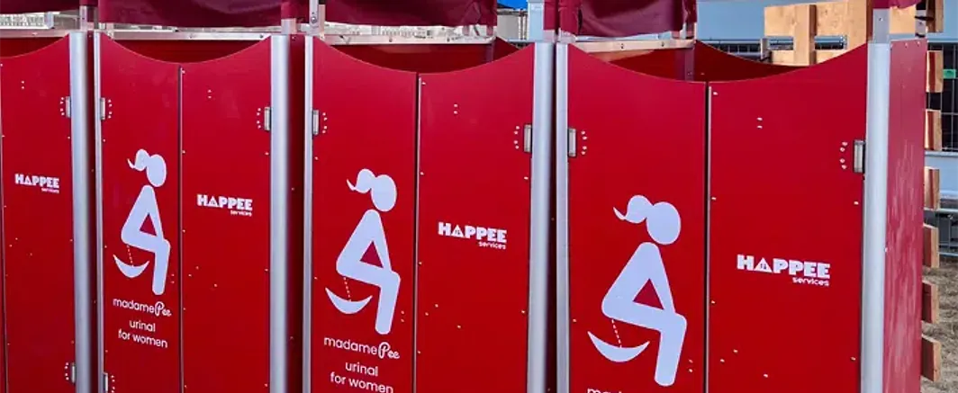 A row of red madamePee units at a festival